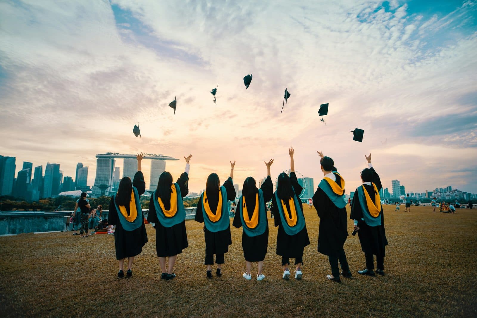 Personas recién graduadas celebrando con sus birretes en alto