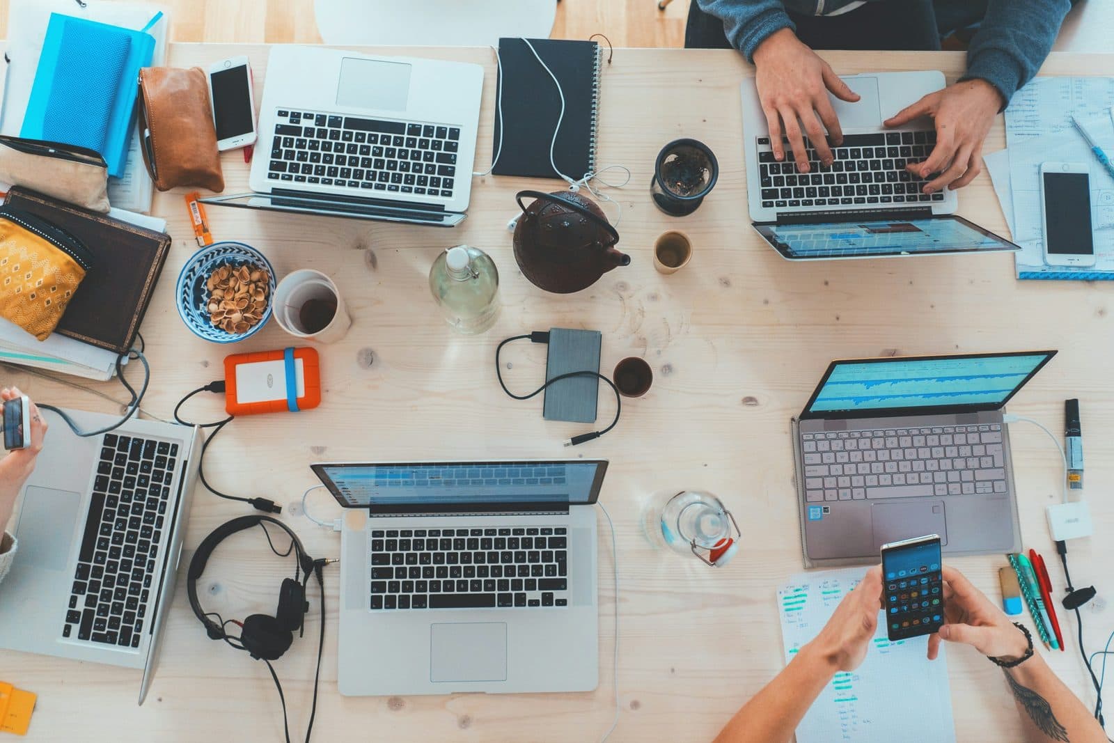 Equipo de estudiantes trabajando alrededor de una mesa con computadoras y notas