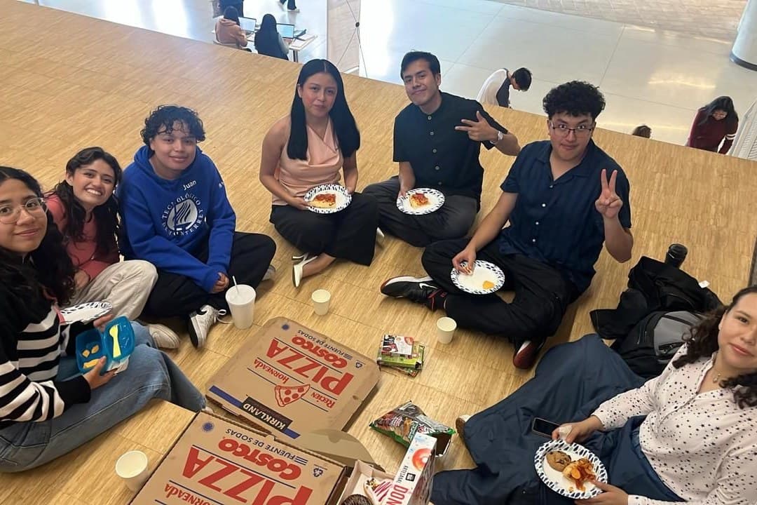 El grupo sentado en el piso del campus compartiendo pizza
